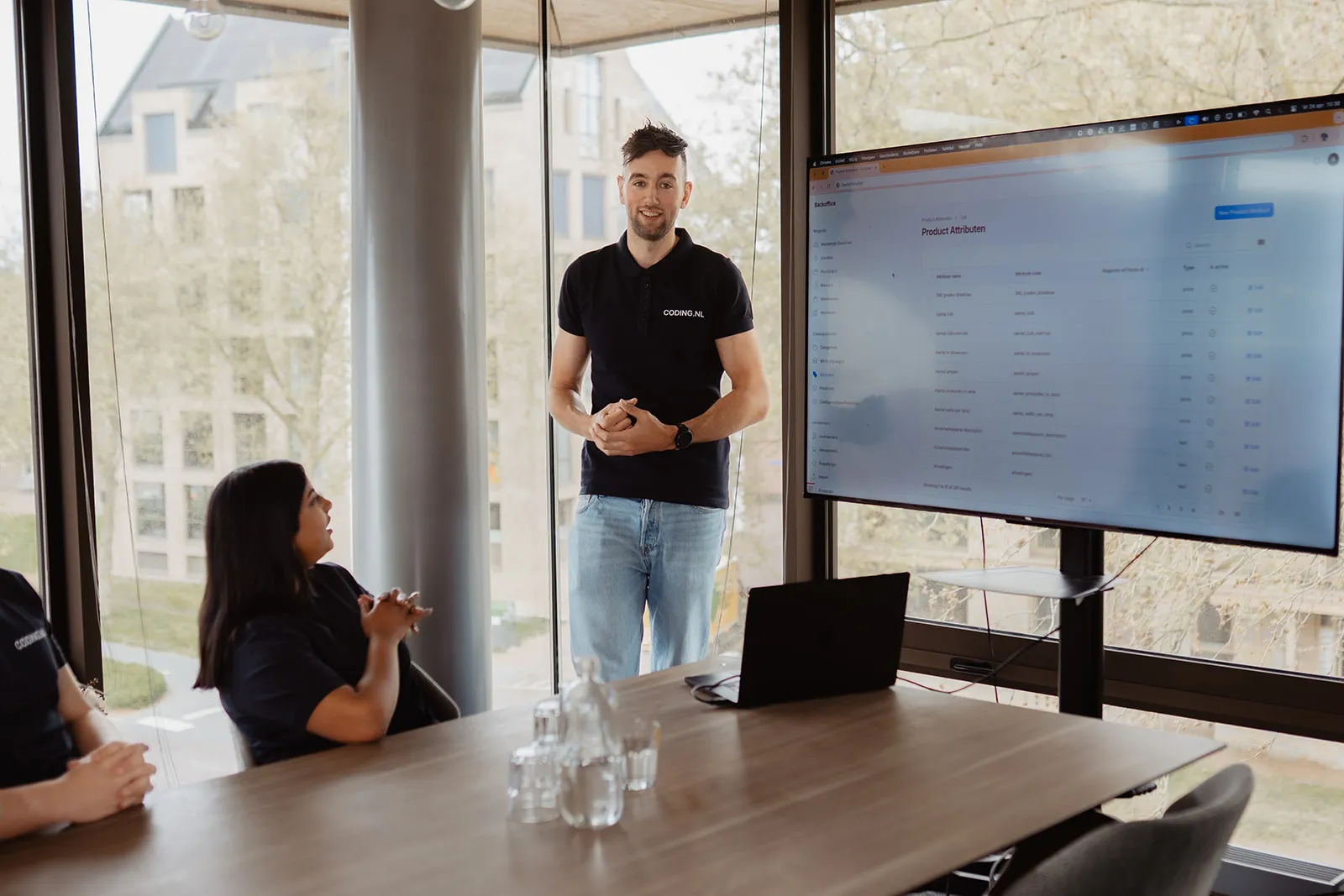 Developer van Coding.nl presenteert een dashboard op een groot scherm